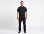 Uniforme Negro Cuello Militar Antifluido Importado Licrado (2) Hombre de pie posando con un uniforme médico negro de dos piezas que incluye una filipina de manga corta con cuello tipo Mao y pantalones rectos a juego.